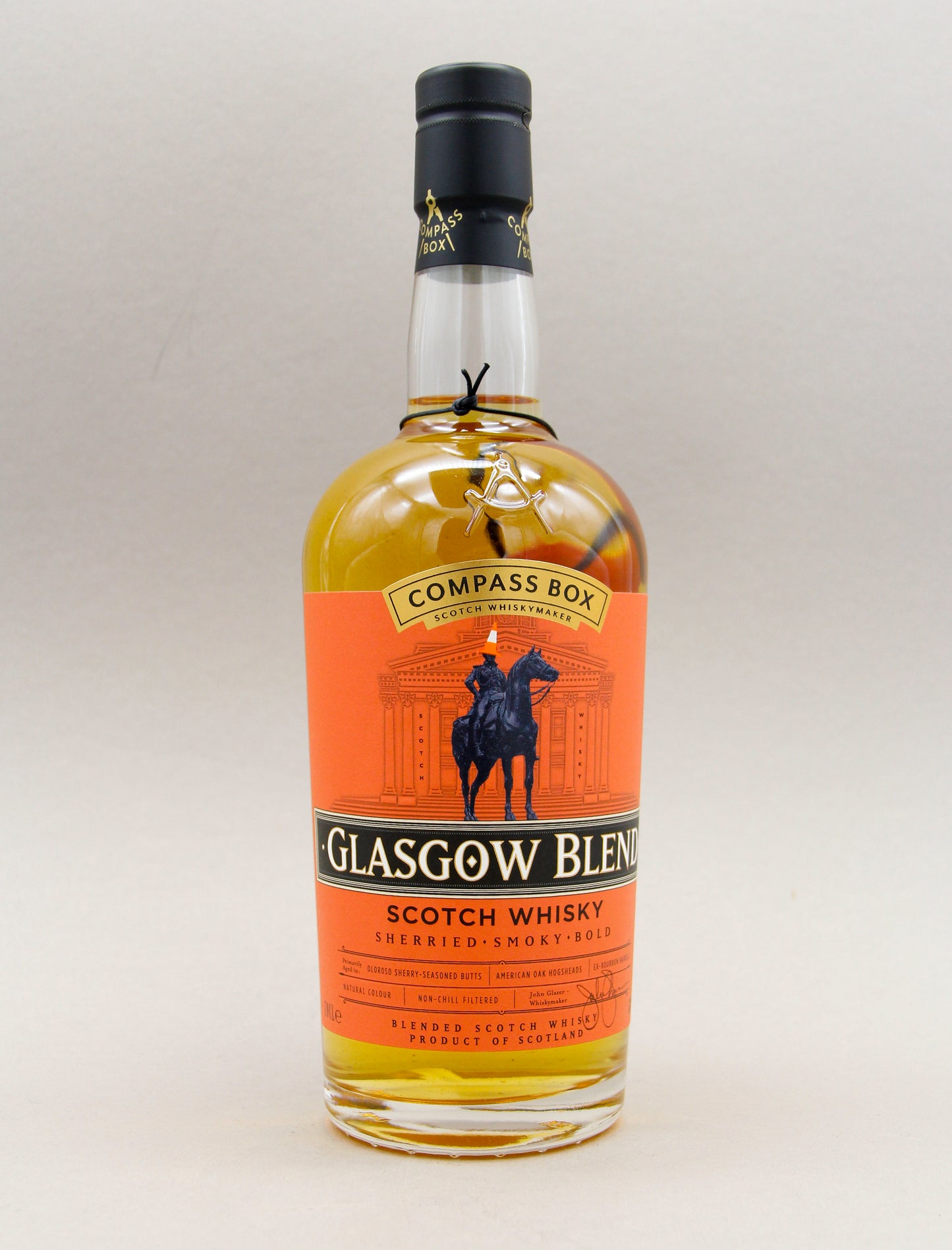 A bottle of Compass Box Glasgow Blend Scotch Whisky with an orange label featuring a rider on horseback and text describing it as “Sherried, Smoky, Bold.”